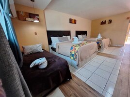 Una habitación de hotel con dos camas, piso de madera y una pequeña mesa.
