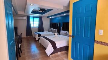 A hotel room with two beds, a dining area, and a bathroom.