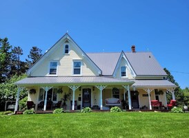 A two-story house with a porch, a welcome sign, and a small garden area.