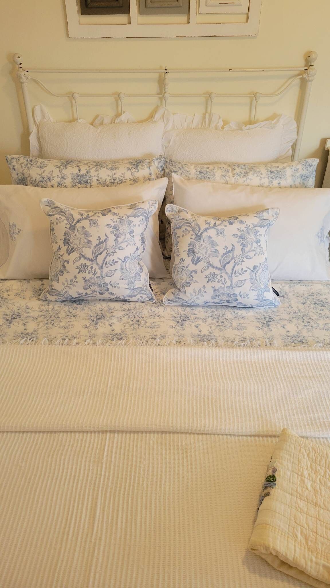 A bed with a white headboard, multiple pillows, and a quilted bedspread.