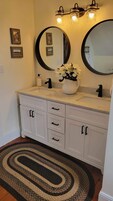 A bathroom with two sinks, a large mirror, and a vase with flowers.