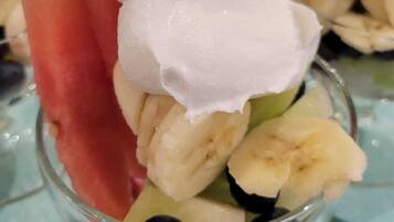 A dessert with whipped cream, watermelon, and bananas in a glass.