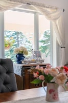 A room with a large window, a table with a vase of flowers, and a decorative tray with glassware.