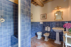 Un baño con azulejos azules, un lavamanos blanco, un bidé y un inodoro.