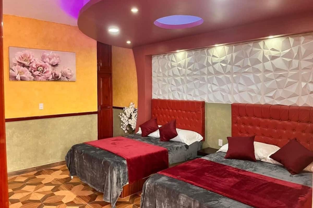 Une chambre d’hôtel avec deux lits, un panneau décoratif au mur et un plafond doté d’un éclairage encastré.