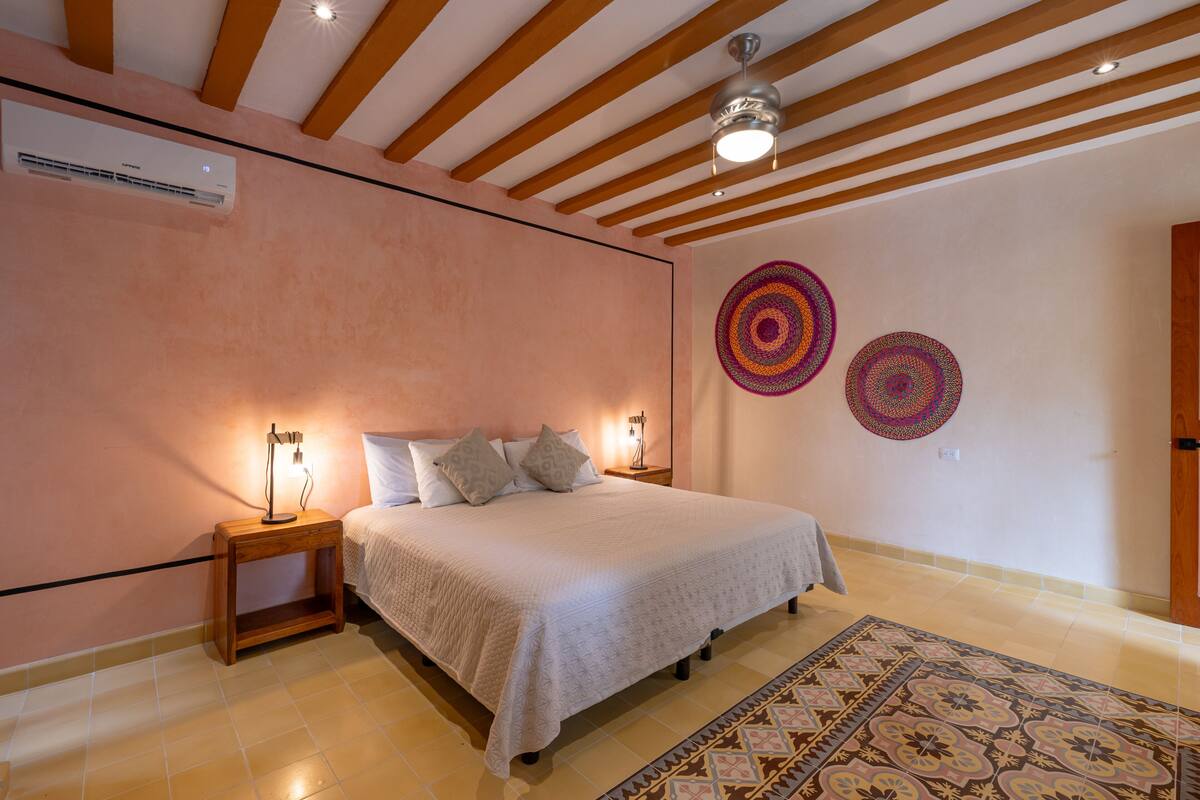 A bedroom with a bed, bedside tables, a ceiling fan, and decorative wall art.