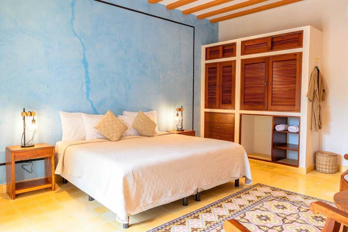 A bedroom with a bed, nightstands, a wardrobe, and a patterned rug.