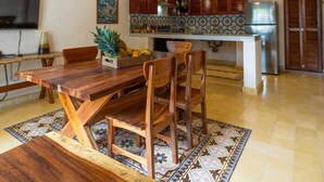 A spacious dining area with a wooden table and chairs, a ceiling fan, and a kitchen in the background. - Casa Pakal (Valladolid)
