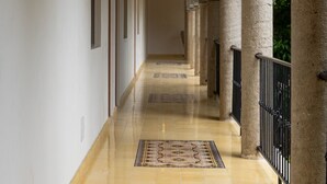 A corridor with a tiled floor, wooden ceiling beams, and stone columns. - Casa Pakal (Valladolid)