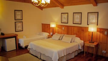 A cozy bedroom with two single beds, wooden paneling, a desk, and a refrigerator.