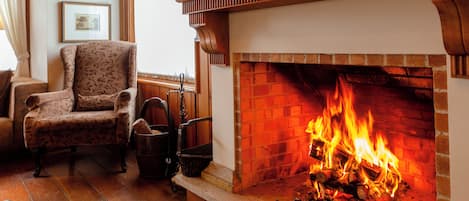 A cozy living room with a fireplace, a patterned armchair, and a wooden floor.