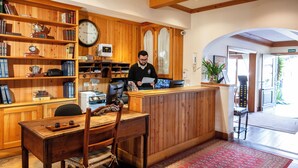 Un interior de madera con una mesa de recepción, un reloj y una estantería.
