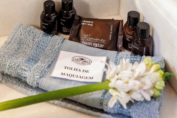 A towel with a label, toiletries, and a flower on a bathroom counter.
