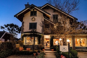 A two-story building with a stone facade, a visible entrance, and a sign indicating it is a hotel.
