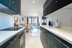 Een moderne keuken met een centraal eiland, inbouwapparatuur en een zithoek met een bank en stoelen.