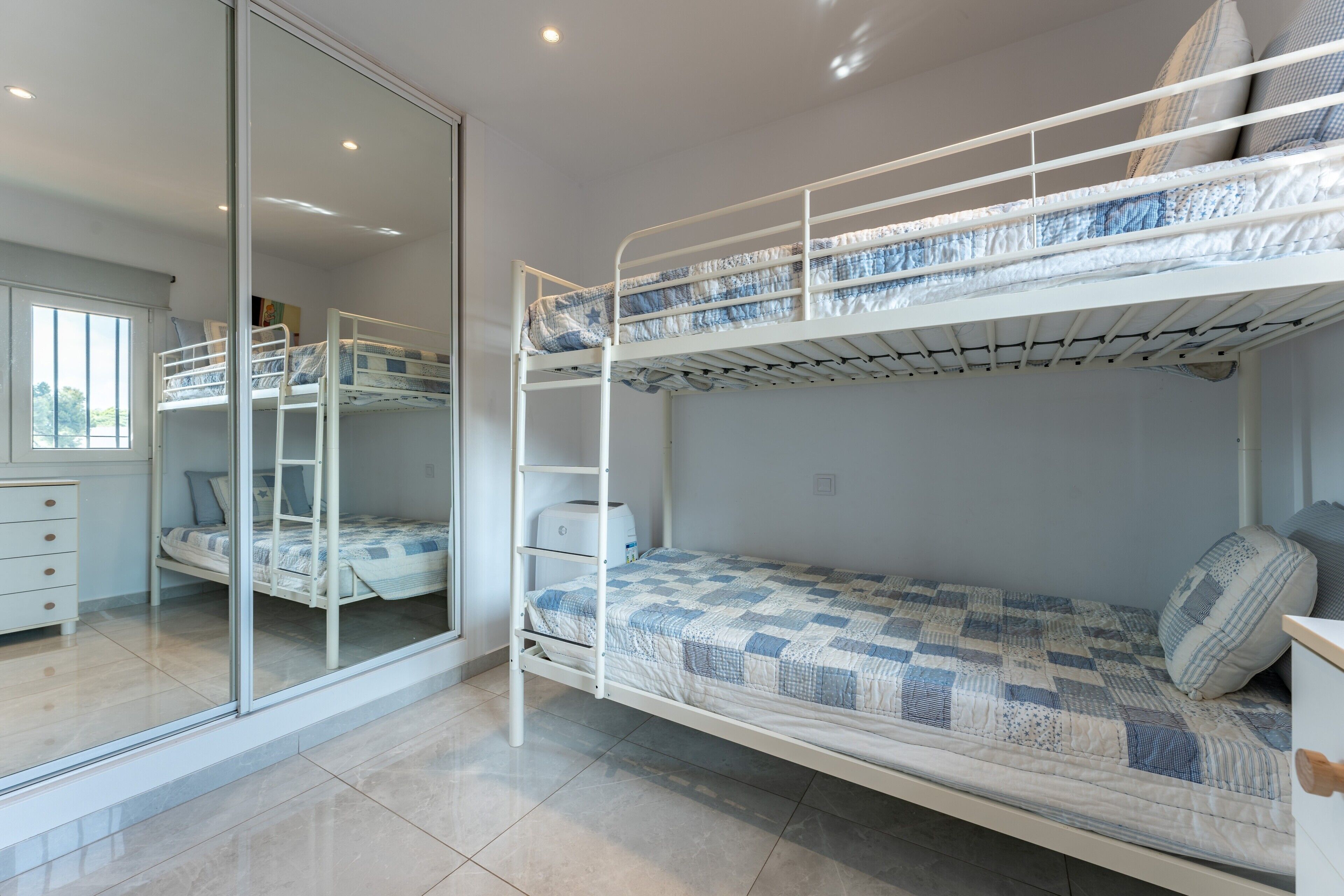A bunk bed room with a window, a desk, and a chair.