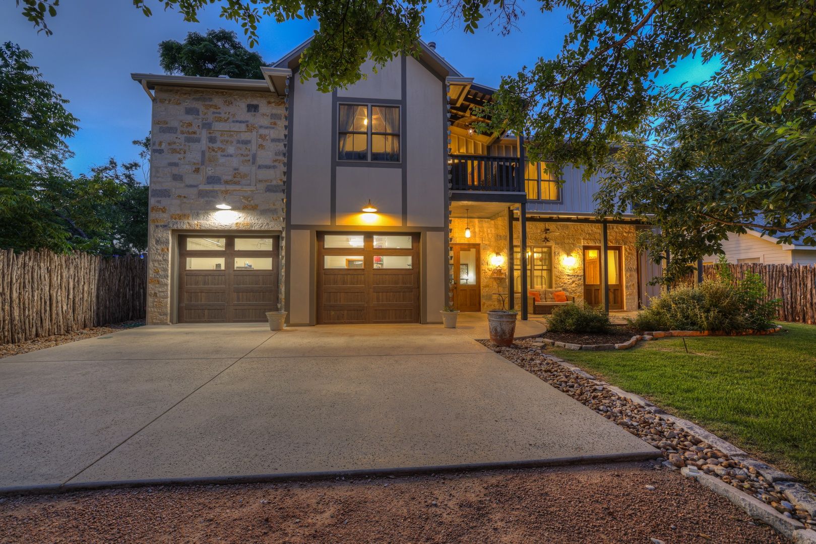 A two-story house with a stone facade, a balcony, and a well-lit entrance.