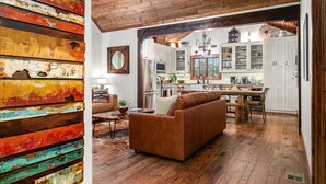 Un intérieur rustique avec des planchers en bois, un canapé en cuir marron et des meubles blancs.