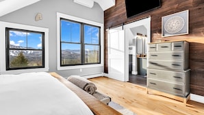 A bedroom with a large bed, wooden floor, and a view of mountains through two large windows. - 3 Min to Slopes  | Stunning Mountain View (Newry)