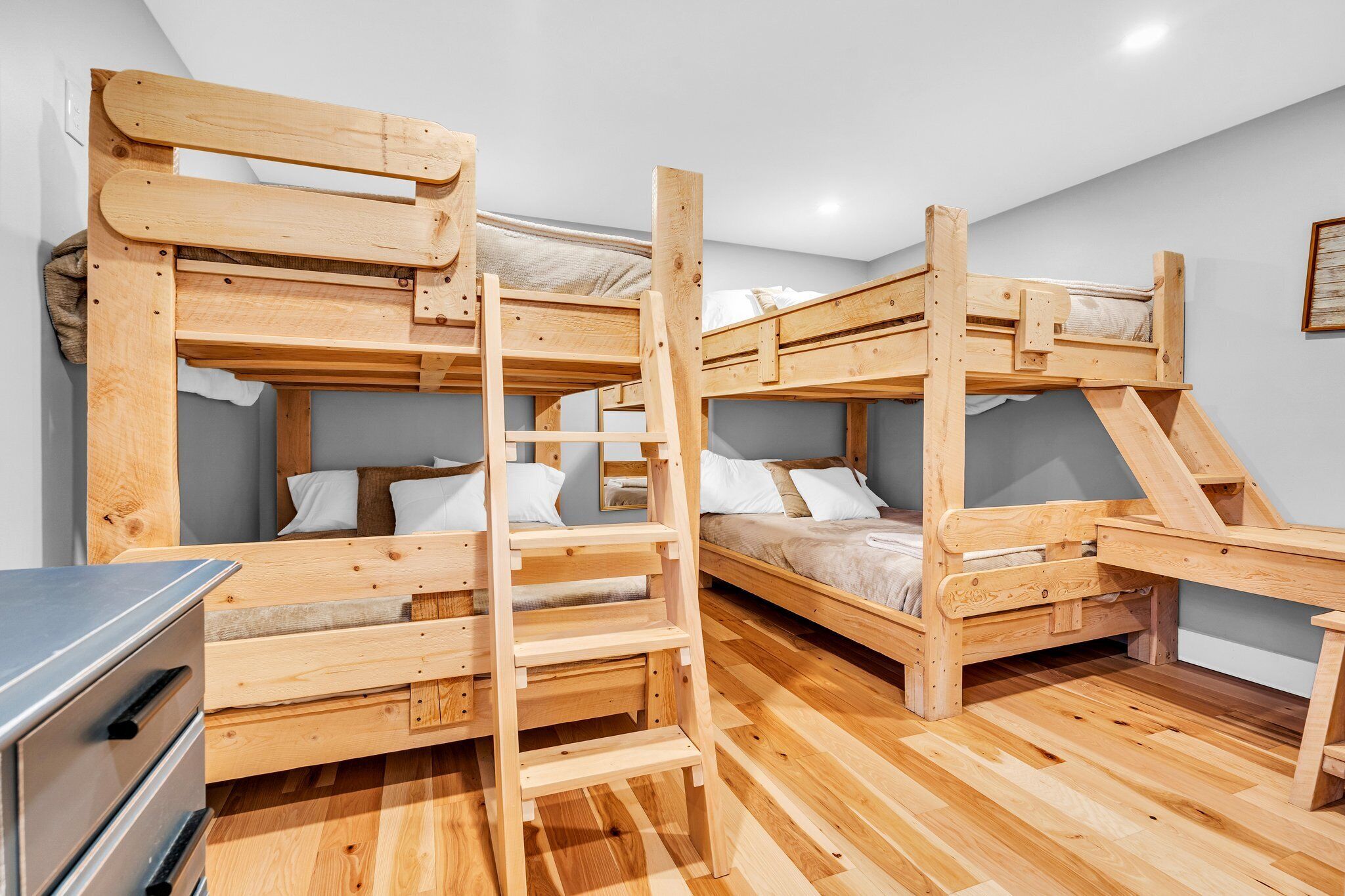 A bunk bed room with wooden frames and a small desk.