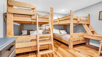 A bunk bed room with wooden frames and a small desk.