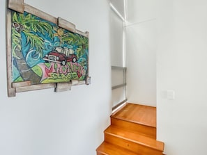 A wooden staircase with a colorful mural on the wall. - 1 Bright Point Townhouse 3103 (Nelly Bay)