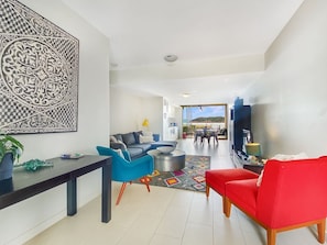 A modern living room with a sofa, a red chair, a coffee table, and a decorative wall piece. - 1 Bright Point Townhouse 3103 (Nelly Bay)