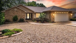 A two-story house with a brick exterior, a front porch, and a driveway leading to a garage.