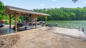 A covered dock with a boat, a grill, and outdoor seating.