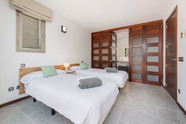 A hotel room with two beds, a large mirror, and a wardrobe with frosted glass panels. - Villa Alfa (Puerto Pollensa)