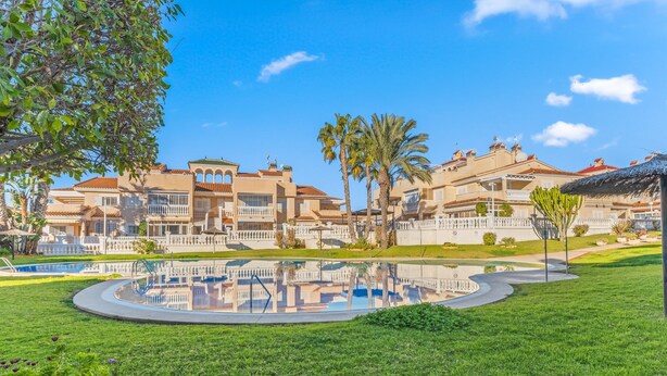 Ein Hotel mit Pool, Palmen und blauem Himmel.