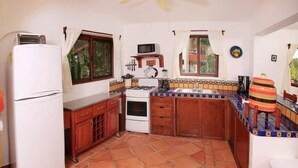 A compact kitchen with a refrigerator, stove, microwave, and tiled backsplash.