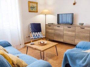 Quarto com sofá, cadeira, mesa, televisão e armário.