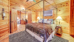 A wooden cabin bedroom with a four-poster bed, a ceiling fan, and a window with blinds. - Waterfront Watauga Lake Home w/ Private Dock! (Butler)