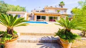 Une villa avec piscine, des escaliers en pierre et des plantes en pot.