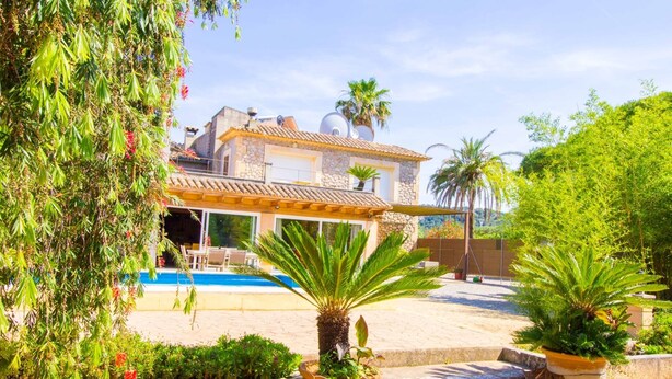 Une villa avec piscine, entourée d’une végétation luxuriante et de palmiers.
