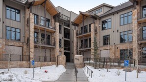 A multi-story building with stone and wood exterior, a wheelchair-accessible entrance, and a snow-covered ground. - Blackstone By Lespri Management  (Park City)