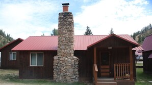 Eine rustikale Holzhütte mit Steinofen, Holzfassade und rotem Dach.