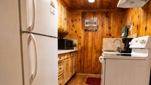 A cabin-style kitchen with wooden walls, a refrigerator, microwave, stove, and cabinets. - Located by the River facing the Mountains (Red River)