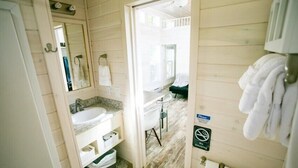 Casa de banho estilo cabana de madeira, com lavatório, espelho e porta-toalhas.