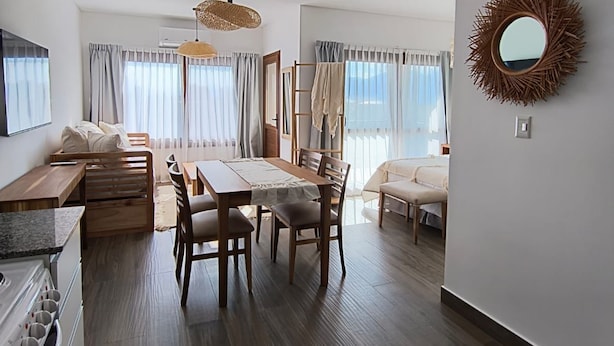 A modern living room with a dining area, wooden furniture, and a large mirror on the wall. - Buena Vid by Chadel Management (Cafayate)