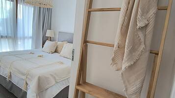 Un dormitorio con cama, lámpara colgante y estante de madera con una manta.