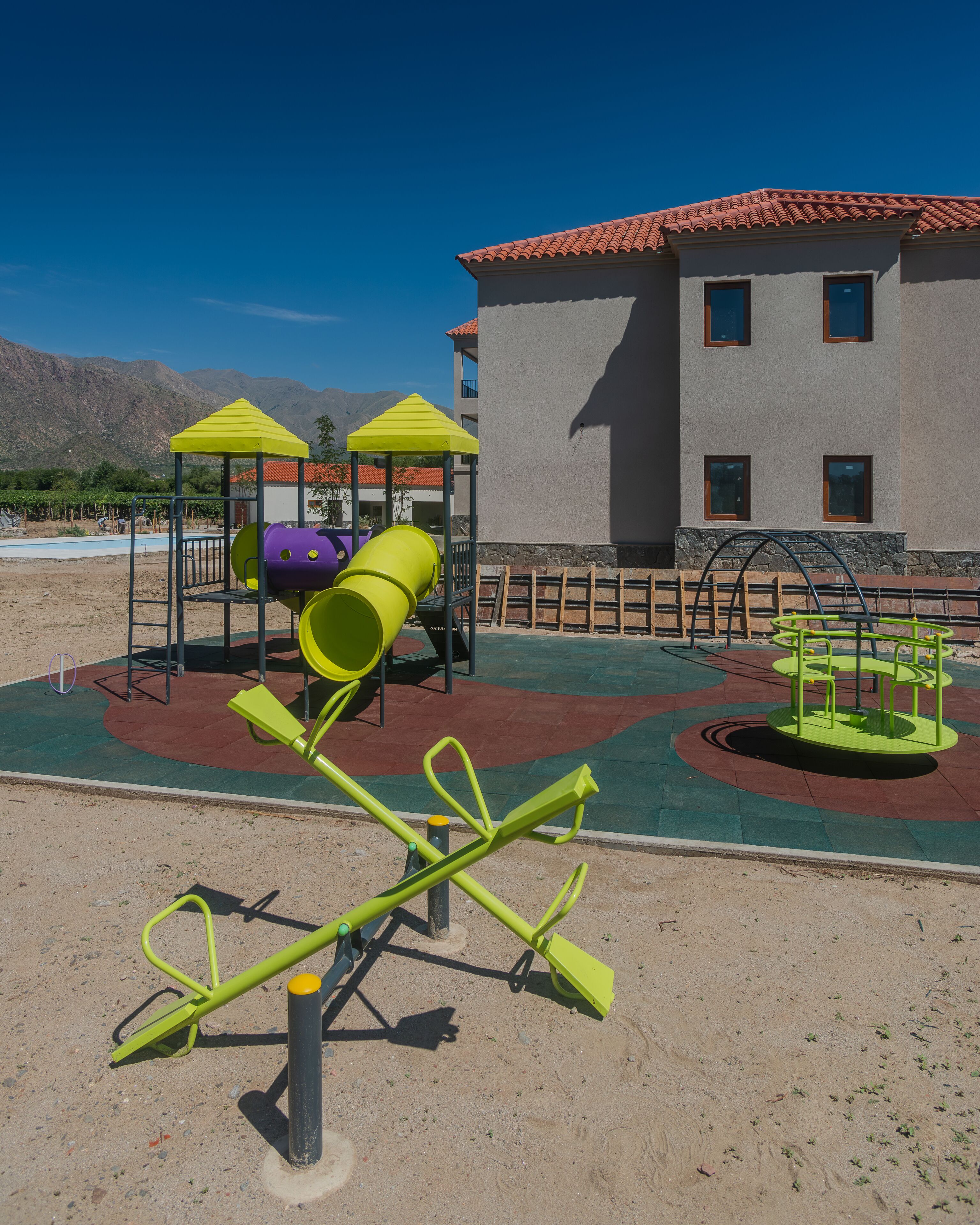 Un parc infantil amb cadira de balanç, tobogan i estructura per escalar.