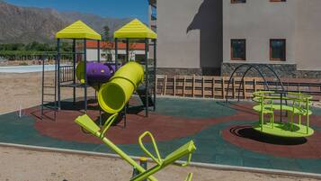 Un parc infantil amb cadira de balanç, tobogan i estructura per escalar.
