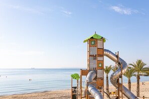 Une plage avec une aire de jeux, des palmiers et un ciel dégagé.