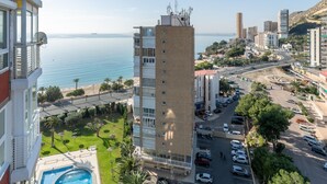 A high-rise building with a swimming pool, parking area, and a view of the sea. - Apartment 'Urbanización Las Torres' with Sea View, Wi-Fi and Air Conditioning (Alacant)