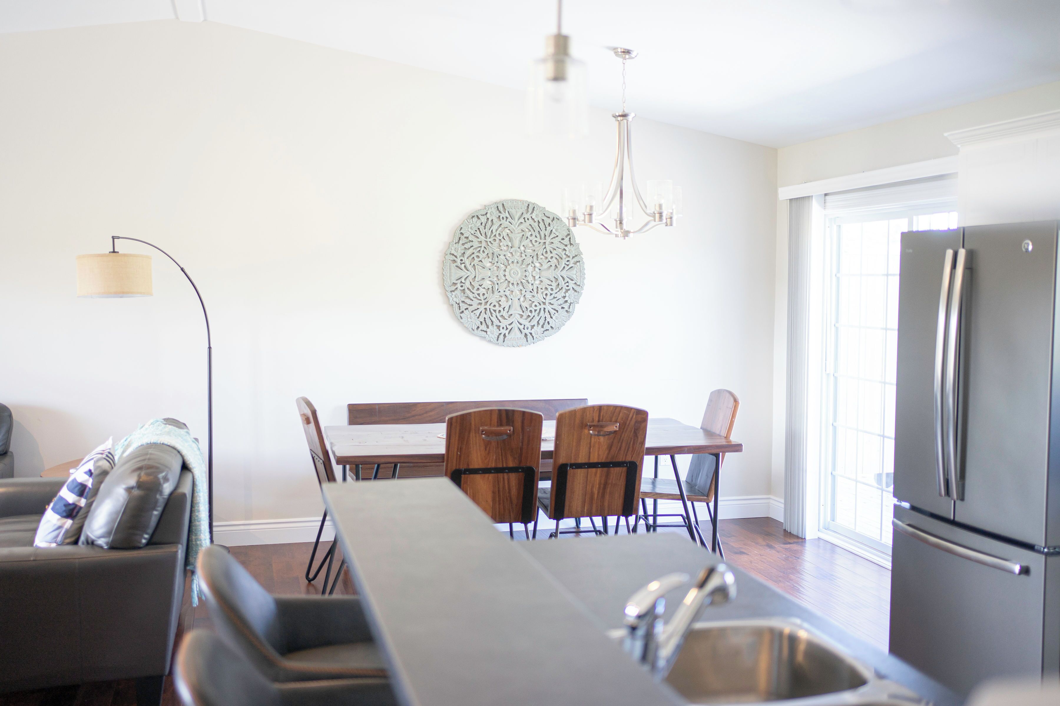 A modern kitchen with a dining area, stainless steel appliances, and a chandelier.