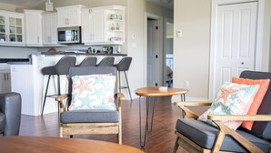 A modern kitchen with white cabinets, a microwave, and a dining area with a wooden table and two chairs.