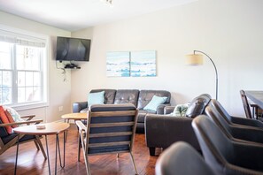 A living room with a sofa, armchairs, a TV, and artwork on the wall. - Meadowview Suite @ The Gables of PEI - Bright and Comfortable Suites with Resort Style Amenities (Stanley Bridge)