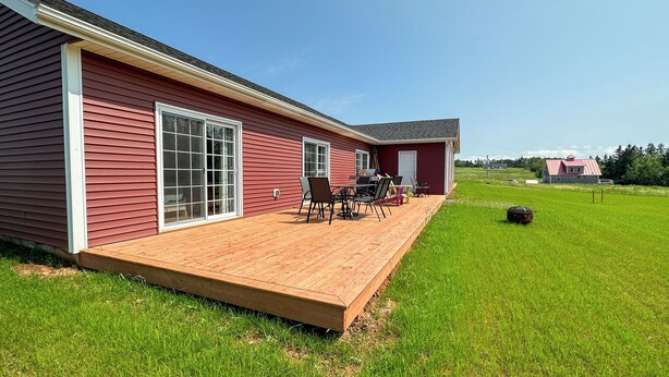 Een rood gebouw met een overdekte patio, een tafel met stoelen en een gazon.